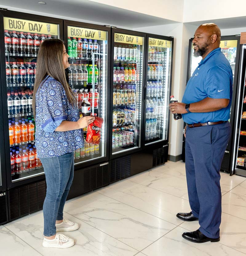 Man and Woman in front of Drink Refrigerators